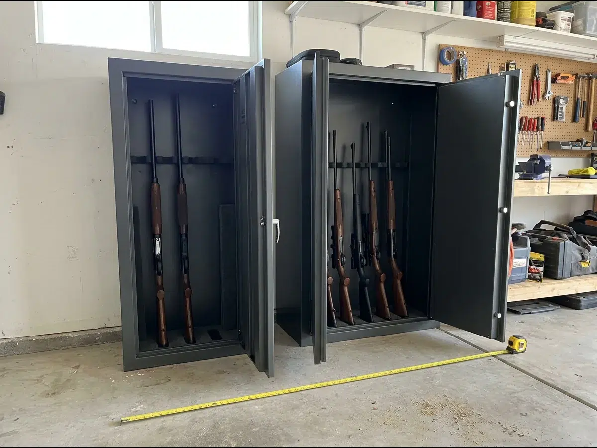 Deux armoires fortes pour armes ouvertes côte à côte dans un garage, une étroite à trois places et une large à huit, un mètre ruban déroulé devant
